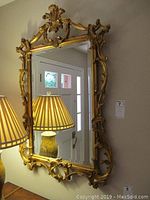 Full view of rectangular mirror hanging on wall with lamps in reflection