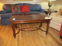 Front view of Maitland Smith coffee table in a room with blue couch and chairs showing overall shape and size.
