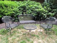 Full view of two wrought iron chairs, bench and round table