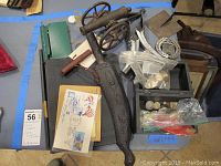 Overview of lot: sundial, toy cannon, knife sheath, boxes and bags of coins