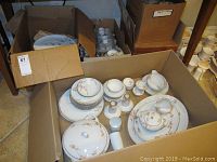 Wide view of boxed Fukagawa Arita porcelain set showing plates, serving dishes, cups, and other pieces.