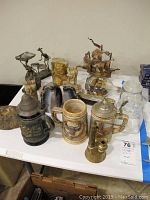 Overview of all items including steins, bookends, model ships, and figurines on table