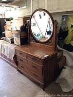Front and side view showing dresser with mounted oval mirror and visible wear on top surface