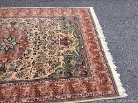 Close-up of the rug's border and floral pattern with visible fringe on the right side.