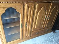 Close-up of front of media storage unit showing glass door with shelves, wood doors, drawer, and detailed molding.