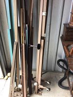 Various wood and metal bed frame parts leaning against a wall in a storage space.