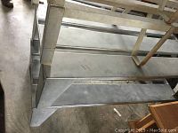 Angle view showing thick metal construction and horizontal support bars of first metal floor stand.