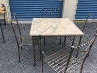 Square patio table with marble top and metal framed chairs arranged around it