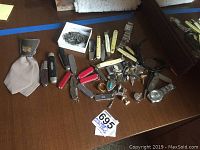 Wide view showing all lot contents on table, including knives, watches, pins, buckle, tie and money clip