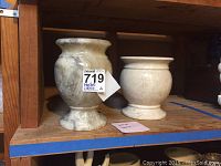 Two Italian marble vases on wooden shelf, showing sizes and condition with visible cracks and damage