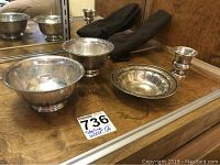 Four silver bowls displayed on wooden surface including three sterling silver and one silver-plated bowl.
