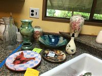 Overview of various ceramic pottery items on kitchen countertop including vases, bowl, plates, and oil decanter