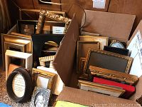 Wide view of multiple assorted picture frames in a box showing various styles and colors.