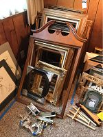 Overall view of the assortment of wooden frames stacked against the wall with three art display lights visible in front of the frames.