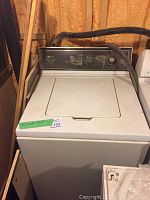 White Maytag top load washing machine with control panel and hoses on top