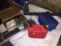 Photo showing small red gas can, reflective sunshade, wooden box with hitch accessories, blue first aid emergency kit, black metal bike rack, and Subaru tow ball