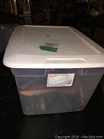 Front view of the clear Sterilite storage bin with white lid showing contents inside.