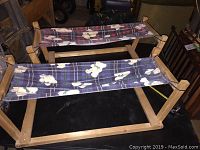 Two wooden frame cat hammocks with fabric beds showing plaid and dog pattern; front and side views.