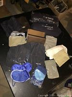Photo of assorted airplane swag items including neck pillows, socks, blankets, and small bags arranged on a table.
