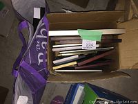 Box containing fourteen assorted picture frames in various sizes and styles stacked together.