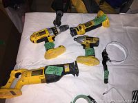Overview of all four DeWalt cordless power tools and the oil change wrench on a white cloth background, showing condition and battery packs separate.