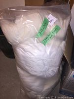 Photo showing seven white pillows in a clear plastic bag with label indicating contents.