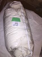 Duvet rolled and packed inside clear plastic cover labeled '202 Queen size down duvet'