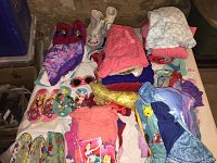 Overview of toddler Disney Princess clothing and accessories spread on table, including footwear, clothing, and towels