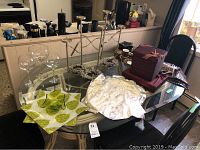 Table display showing wine glasses, metal candle stands, gift boxes, winter decor, and coffee set on a glass topped dining table
