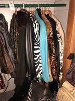 Photo of various women's coats on hangers showing fur, leather, and animal-printed styles including leopard and zebra motifs.