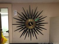 Sun shaped wall clock hung on wall with visible rays and clock face.