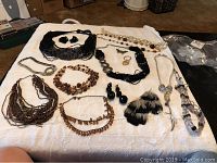 Full lot view showing all items spread on a white cloth including necklaces, earrings, and rings together.