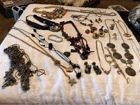 Full overview of approximately 30 vintage costume jewelry pieces including necklaces, bracelets, and earrings arranged on white surface.