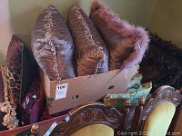 Four assorted cushions in a cardboard box including quilted mauve pattern and faux fur trimmed cushions