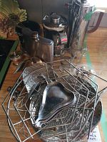 Various metal and stainless steel kitchen and decor items including flask, coffee pot, and serving dishes displayed together