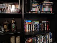 Photo of multiple DVD box sets on shelves including Tony Robbins Personal Power II and assorted DVDs.