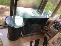 Photo showing the large rectangular table and smaller round side table with glass tops and carved bases. The large table base features an elephant and tropical leaf carvings.