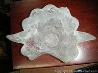 Top view of the white translucent Murano glass dish with floral design and gold trim placed on a wooden surface.