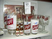 Overall view of Schlitz barware collection including glasses, pitcher, shakers, and vintage ad.