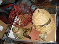 Photo showing red metal wire apple-shaped holder, woven hive-shaped basket, signed pottery teapot and ceramic star-shaped trivet.