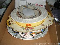 Stack of five assorted decorative porcelain plates showing varied floral patterns and shapes.