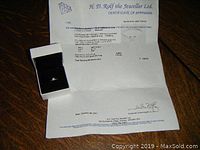Ring and certificate of appraisal on wooden surface