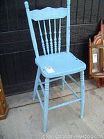 Full view of the vintage pressback wooden chair showing the full height, seat, and legs painted light blue with signs of wear.