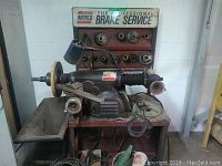 Full view of Ammco brake lathe on steel stand showing lathe head, adapter rack, shavings tray and lamp