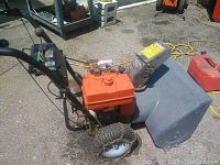 Left side view of orange Sears C950 snowblower with tire chains, black handle, and gray metal snow intake and chute.
