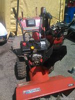 Front three-quarter view of Murray red and black snowblower showing engine, controls, auger housing and tires