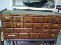 Front view of oak wood cabinet with 30 small drawers on metal stand