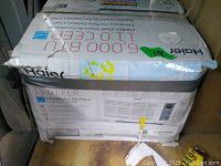 Original box of Haier 6000 BTU window AC unit showing the brand, model, specifications, and exterior damage to the box.