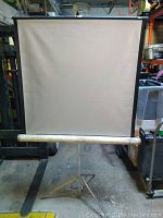 Front view of vintage Knox Regent projection screen showing the screen fabric, roller and tripod stand.