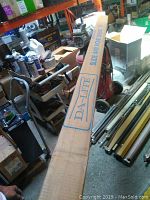 Long view of the boxed projection screen with Da-Lite branding in a workshop setting.